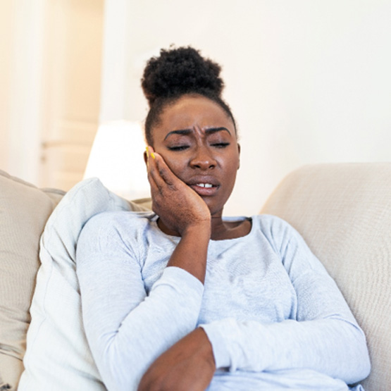 Woman with toothache sitting on couch at home