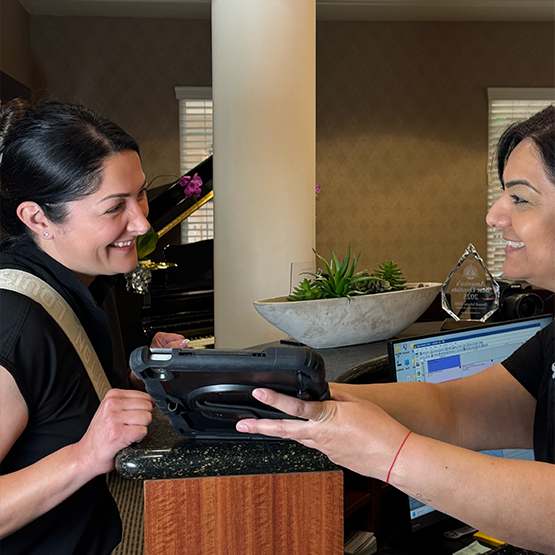 Two dental team members standing in front of wall and smiling