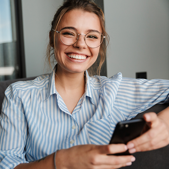 Woman with glasses and striped shirt sitting on couch and smiling