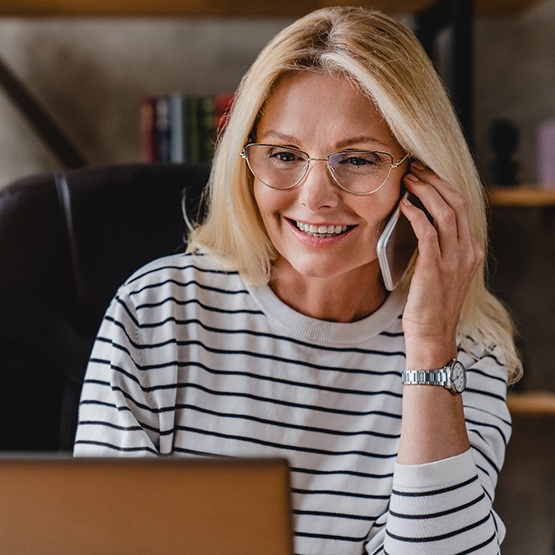 Woman with glasses smiling while talking on phone
