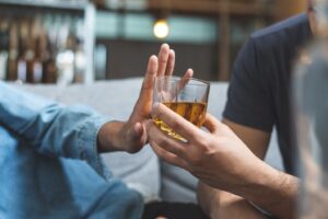 Person turning down alcohol offer from another person.